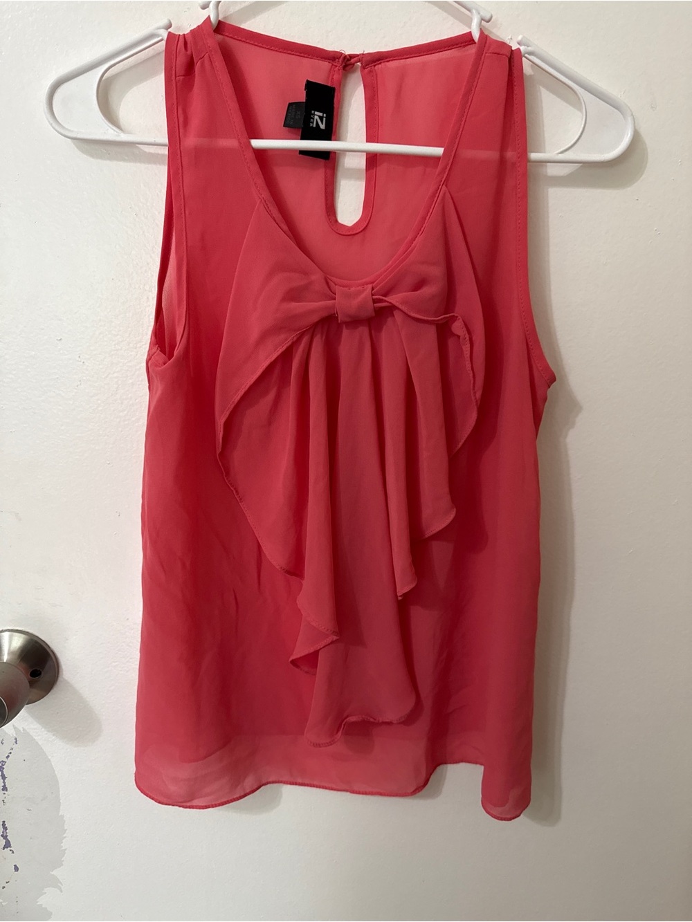 Sheer pink sleeveless blouse with bow accent.